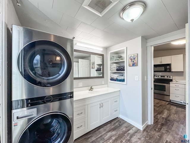 clothes washing area featuring stacked washer and dryer and dark hardwood / wood-style flooring