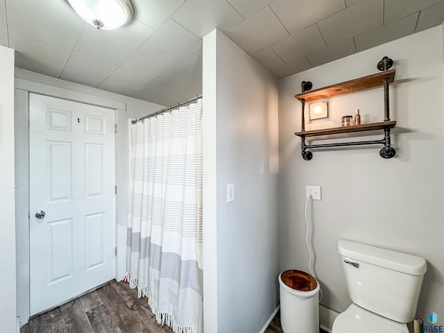 bathroom with hardwood / wood-style flooring, a shower with shower curtain, and toilet