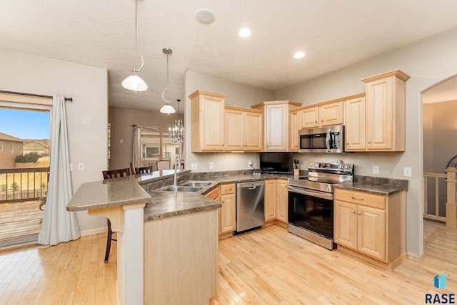 kitchen featuring appliances with stainless steel finishes, a breakfast bar, pendant lighting, sink, and kitchen peninsula