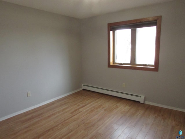 empty room featuring a baseboard radiator and light hardwood / wood-style floors