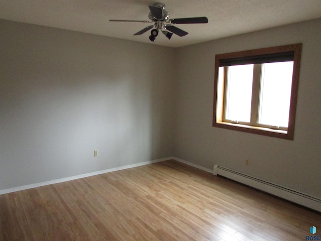 empty room featuring baseboard heating, ceiling fan, and light wood-type flooring