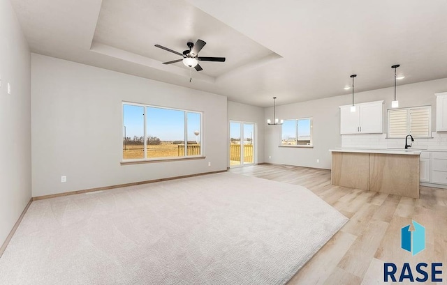 1004 N Juniper St, Lennox, SD 57039 - unfurnished living room with plenty of natural light, a tray ceiling, and ceiling fan with notable chandelier