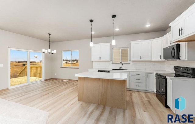 1004 N Juniper St, Lennox, SD 57039 - kitchen with white cabinetry, sink, black appliances, and a kitchen island
