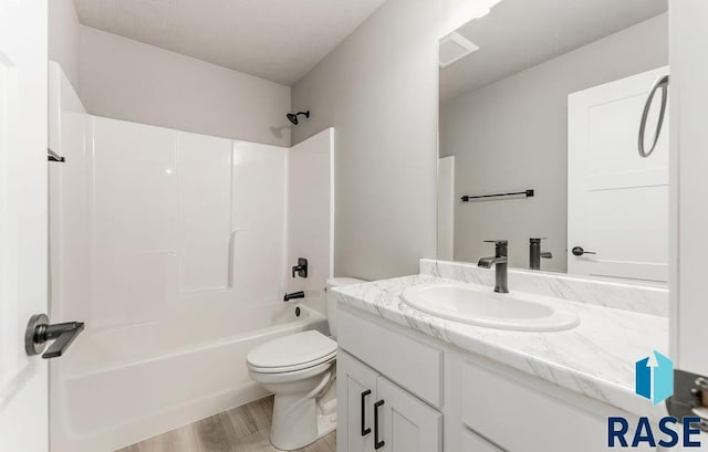 full bathroom with hardwood / wood-style flooring, shower / washtub combination, toilet, and vanity