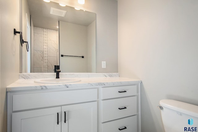 bathroom featuring vanity, a shower, and toilet