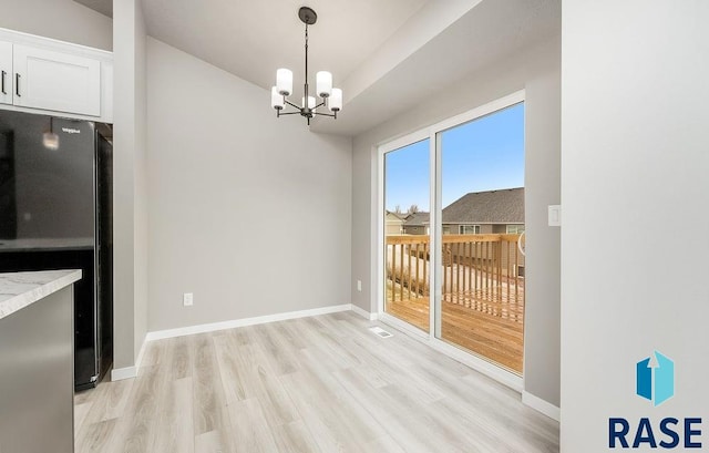 unfurnished dining area with an inviting chandelier and light wood-type flooring