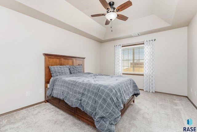 bedroom featuring light colored carpet, ceiling fan, and a tray ceiling