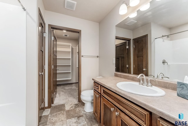 bathroom featuring vanity, a shower, and toilet