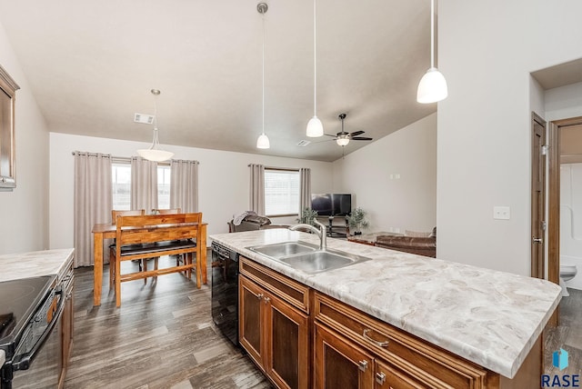 kitchen featuring sink, decorative light fixtures, dark hardwood / wood-style flooring, a kitchen island with sink, and black appliances