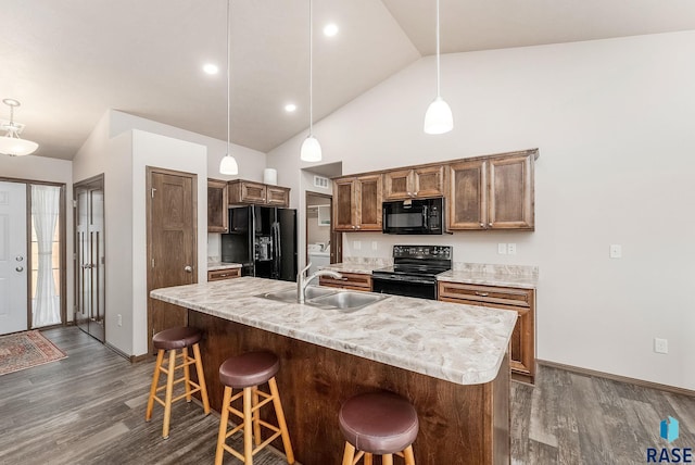 kitchen featuring a center island with sink, sink, pendant lighting, and black appliances