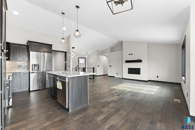 kitchen with sink, decorative light fixtures, appliances with stainless steel finishes, dark hardwood / wood-style flooring, and a kitchen island with sink