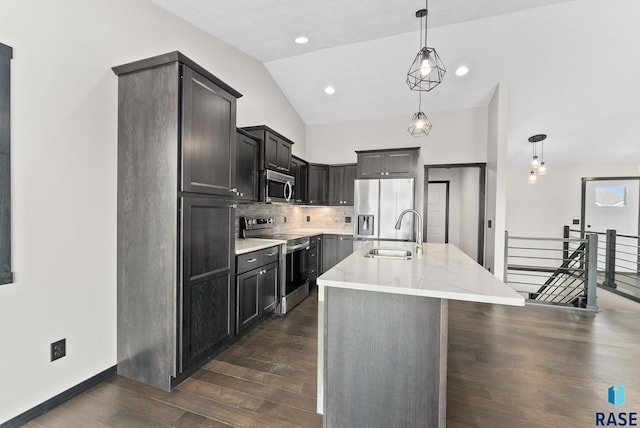 kitchen with an island with sink, appliances with stainless steel finishes, sink, and decorative light fixtures