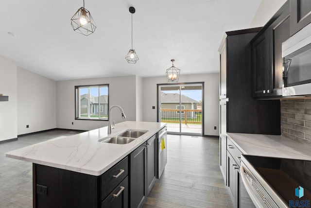 kitchen featuring sink, tasteful backsplash, hanging light fixtures, appliances with stainless steel finishes, and an island with sink