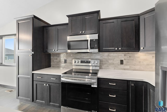 kitchen with stainless steel appliances, light stone countertops, and decorative backsplash