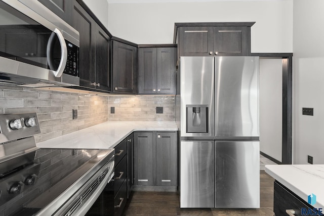 kitchen featuring stainless steel appliances, dark hardwood / wood-style flooring, light stone counters, and decorative backsplash