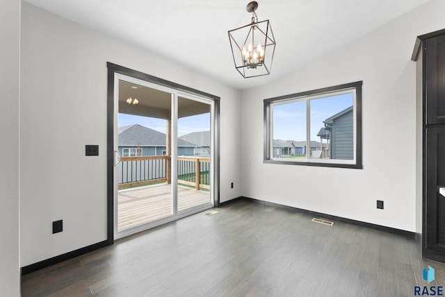 spare room featuring an inviting chandelier, lofted ceiling, and dark hardwood / wood-style floors