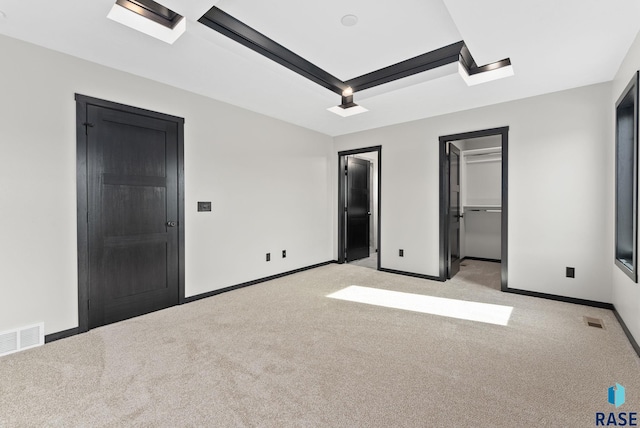 unfurnished bedroom featuring a walk in closet and light carpet