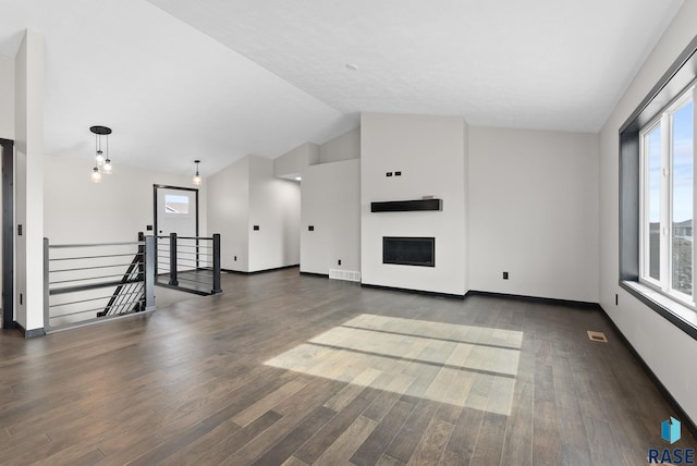 unfurnished living room with dark hardwood / wood-style flooring, plenty of natural light, and lofted ceiling