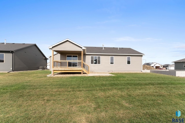 rear view of house featuring a wooden deck and a yard