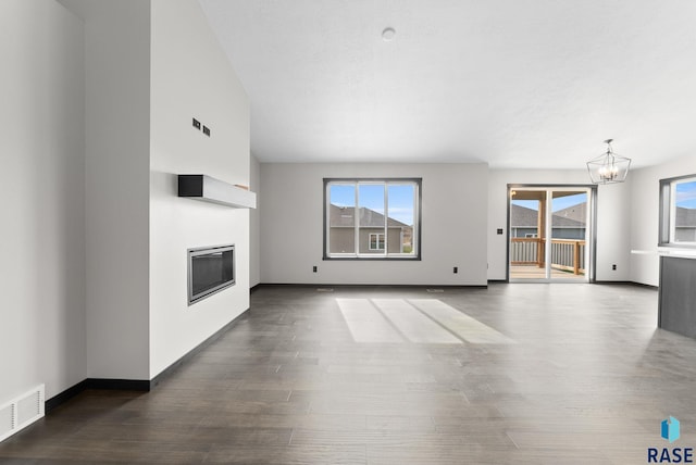 unfurnished living room featuring dark hardwood / wood-style flooring and a notable chandelier