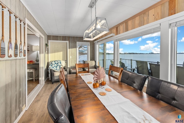 dining space with crown molding, a water view, and light hardwood / wood-style floors