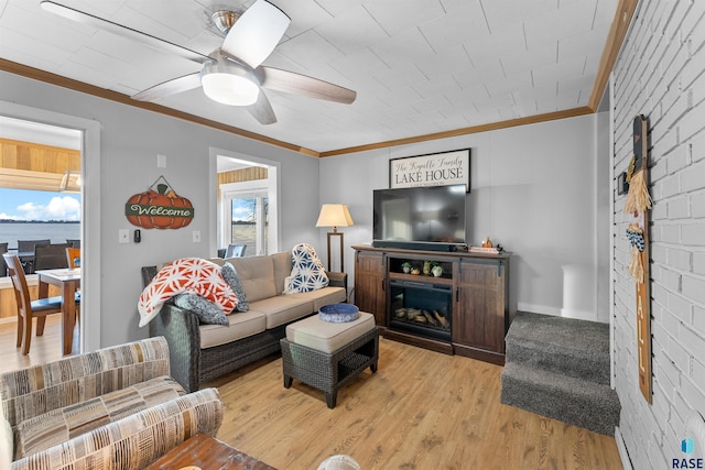 living room featuring crown molding, light hardwood / wood-style floors, ceiling fan, and brick wall