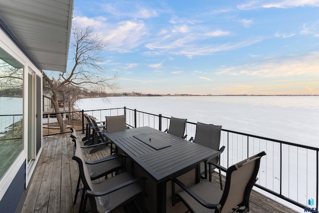 deck at dusk featuring a water view