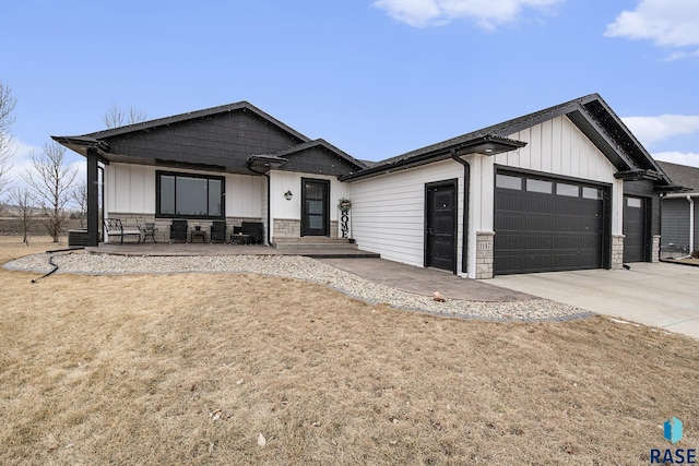 view of front of property featuring a garage, concrete driveway, stone siding, board and batten siding, and a front yard