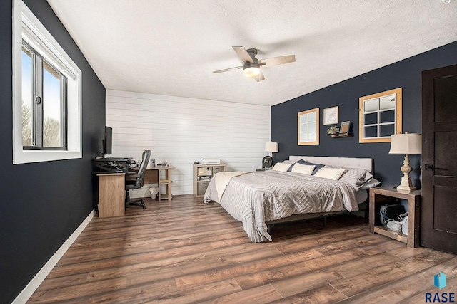 bedroom with ceiling fan, a textured ceiling, baseboards, and wood finished floors