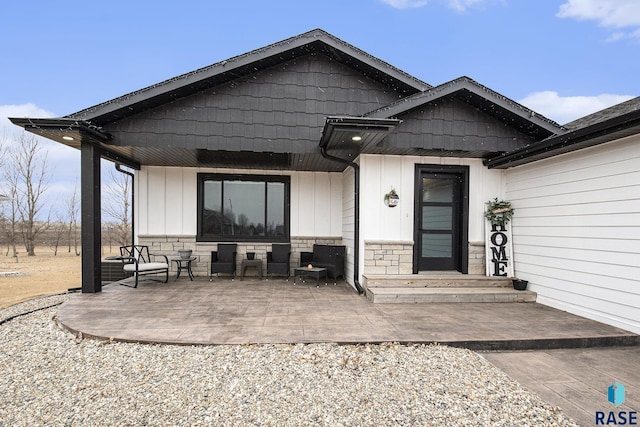 view of front of home with stone siding, covered porch, and board and batten siding