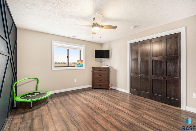 unfurnished bedroom featuring dark wood-type flooring, a textured ceiling, and baseboards