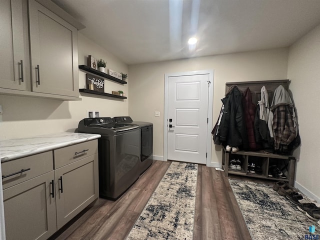 clothes washing area with baseboards, wood finished floors, cabinet space, and washer and dryer