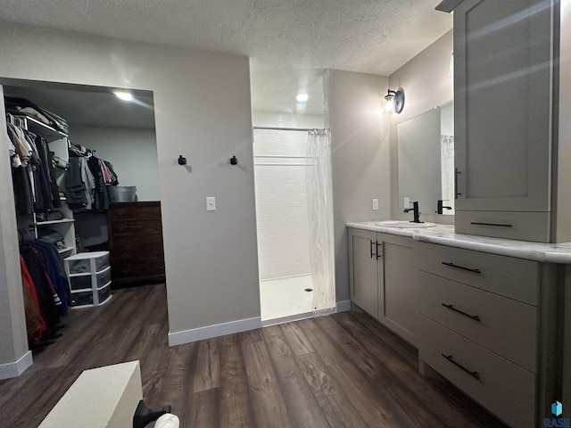 full bath with wood finished floors, a spacious closet, a textured ceiling, a shower stall, and vanity