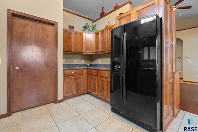 kitchen featuring light tile patterned floors, ornamental molding, and black fridge