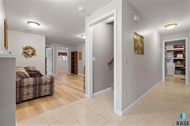 corridor featuring light tile patterned floors and a textured ceiling