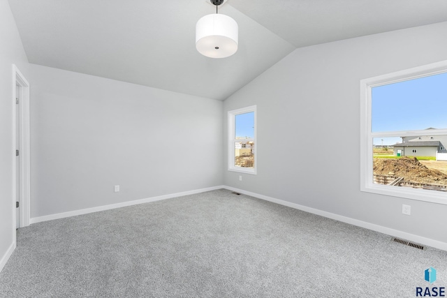 carpeted spare room with vaulted ceiling