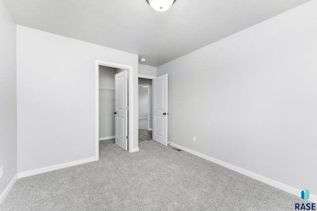 unfurnished bedroom with a spacious closet, light colored carpet, and a closet