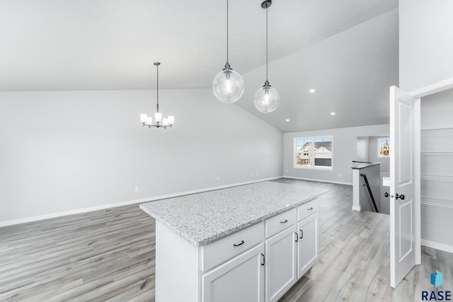 kitchen with white cabinetry, hanging light fixtures, light stone counters, and light hardwood / wood-style floors