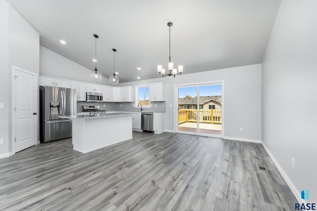 kitchen featuring sink, appliances with stainless steel finishes, hanging light fixtures, white cabinets, and a kitchen island