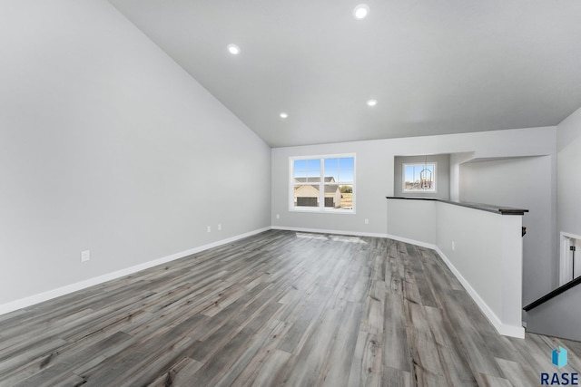 unfurnished living room with lofted ceiling, a chandelier, and light hardwood / wood-style flooring