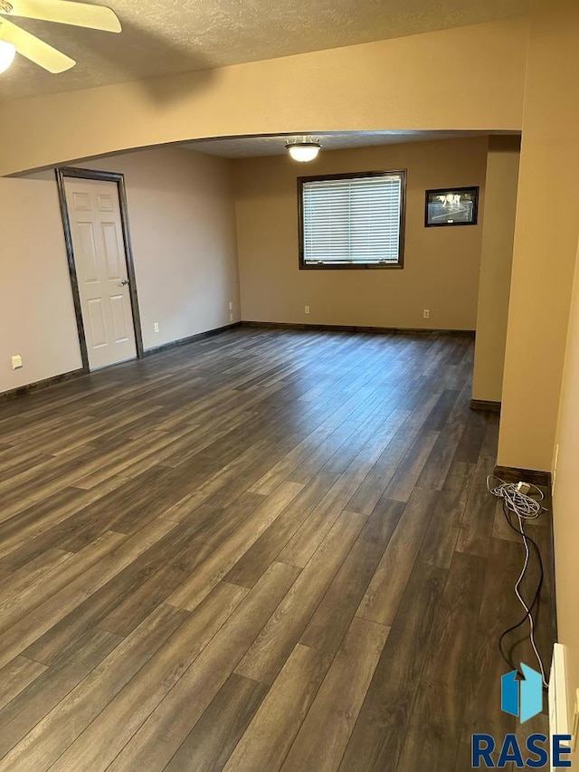 unfurnished room with a textured ceiling, dark hardwood / wood-style floors, and ceiling fan