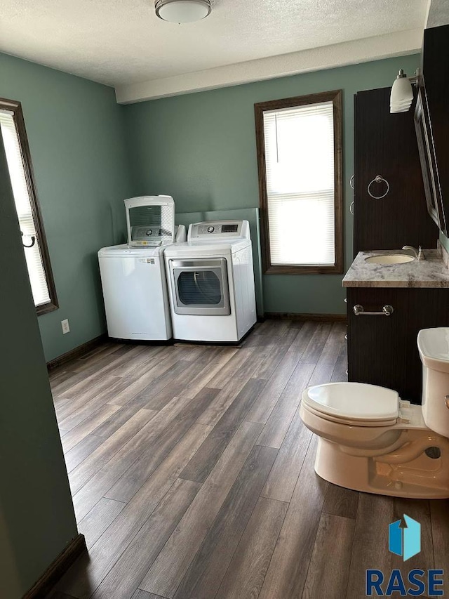 laundry area featuring sink, wood-type flooring, washer and dryer, and a textured ceiling