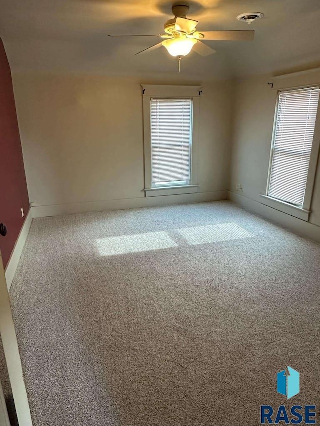 spare room featuring a healthy amount of sunlight, carpet flooring, and ceiling fan