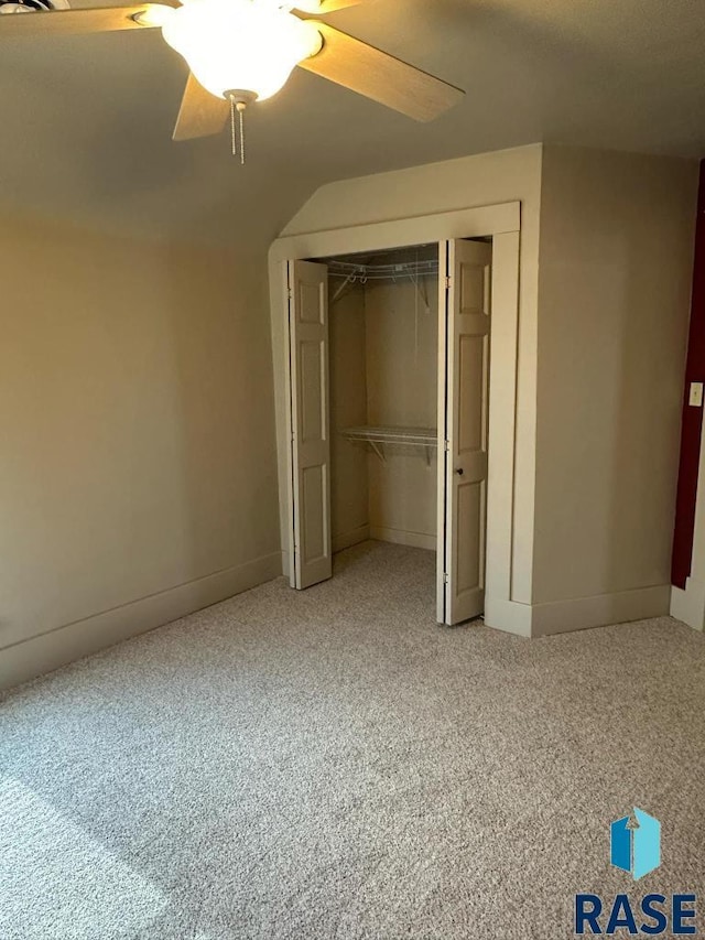 unfurnished bedroom with carpet, lofted ceiling, ceiling fan, and a closet