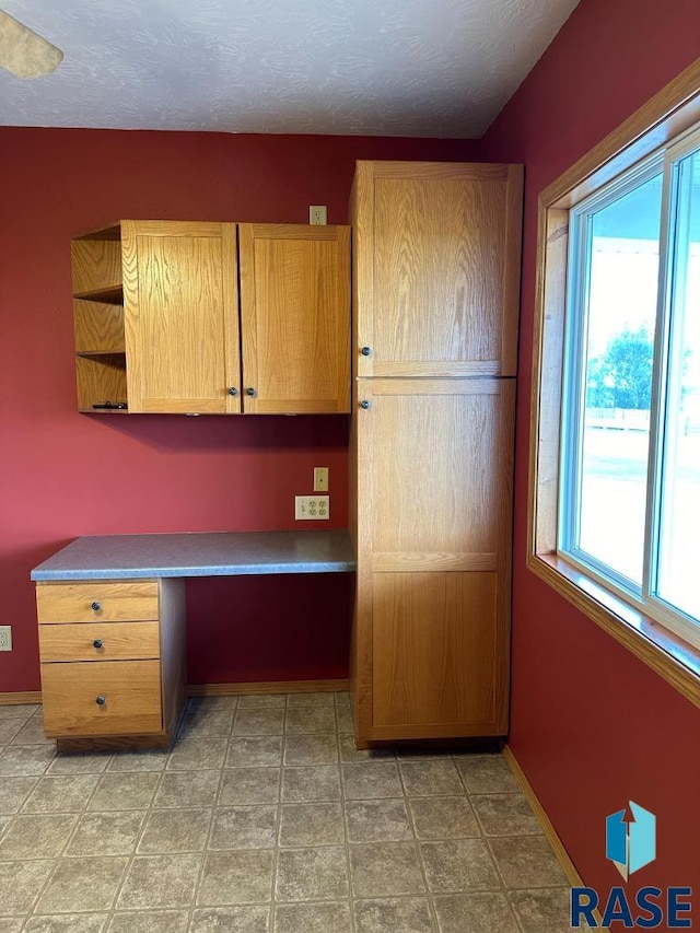 unfurnished office with built in desk and a textured ceiling