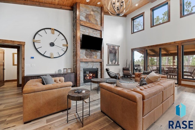 living room featuring light wood-type flooring, a wealth of natural light, wooden ceiling, and a fireplace