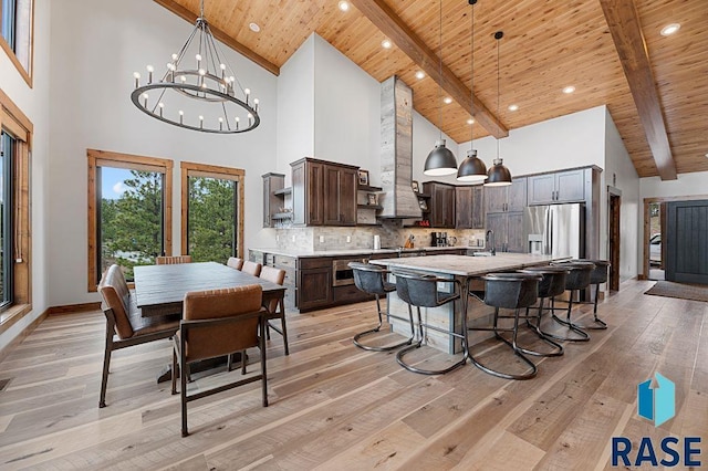 kitchen featuring stainless steel fridge with ice dispenser, hanging light fixtures, dark brown cabinetry, and a kitchen island