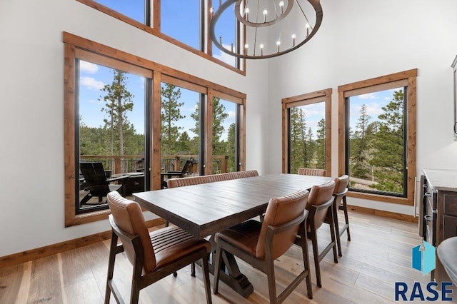 dining space featuring a high ceiling, an inviting chandelier, and light hardwood / wood-style flooring