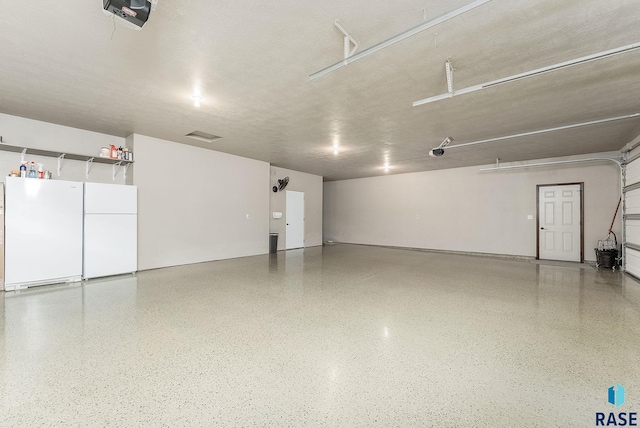 garage with a garage door opener and white fridge