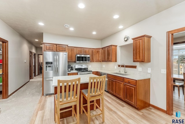 kitchen with sink, a breakfast bar, stainless steel appliances, light stone countertops, and a kitchen island